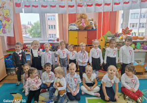 Dzieci pozują do zdjęcia grupowego z kotylionami w barwach narodowych.