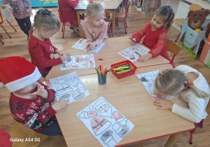 Dzieci wykonują pracę plastyczną z bohaterem dzisiejszego dnia - Św. Mikołajem.