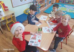 Dzieci wykonują pracę plastyczną z bohaterem dzisiejszego dnia - Św. Mikołajem.