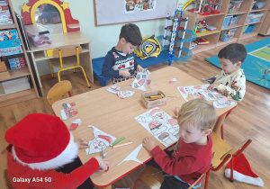 Dzieci wykonują pracę plastyczną z bohaterem dzisiejszego dnia - Św. Mikołajem.