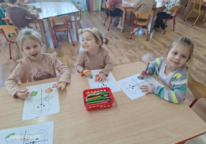 Dziewczynki kolorują puzzle z misiem.
