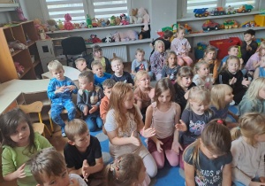 Dzieci siedzą na dywanie i klaszczą