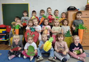 Dzieci pozują do zdjęcia z sylwetami owoców i warzyw.