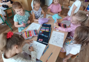 Dzieci siedzą przy stole i kolorują