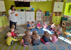Pani psycholog gra z dziećmi w grę na dywanie