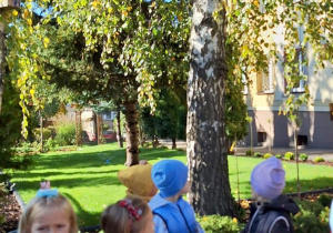 Dzieci stoją pod brzozą.