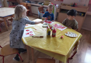 Dzieci wykonują pracę plastyczną techniką stemplowania jabłkiem.