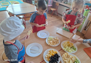 Dzieci komponują szaszłyki owocowe.