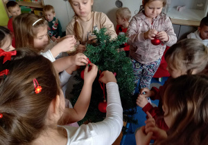 Dziewczynki wieszają bombki na choince