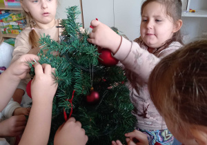 Dziewczynki wieszają bombki na choince