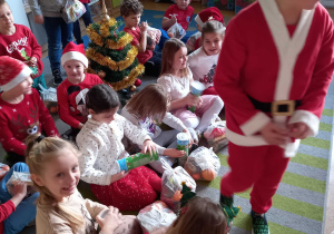 Oliwier przebrany w strój Mikołaja rozdaje dzieciom paczki