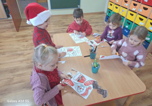 Dzieci wykonują pracę plastyczną z bohaterem dzisiejszego dnia - Św. Mikołajem.