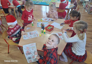 Dzieci wykonują pracę plastyczną z bohaterem dzisiejszego dnia - Św. Mikołajem.