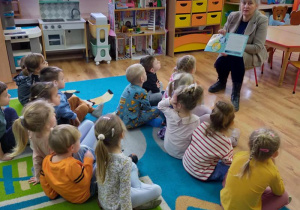 Dzieci słuchają książeczki czytanej przez p. Bibliotekarkę.