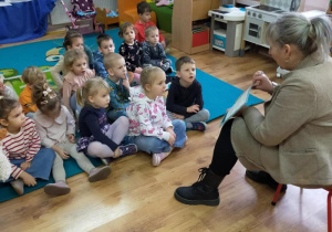 Dzieci słuchają książeczki czytanej przez p. Bibliotekarkę.