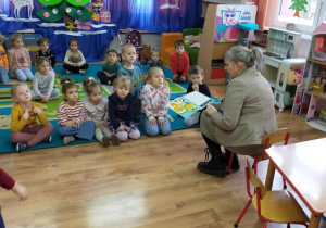 Dzieci słuchają książeczki czytanej przez p. Bibliotekarkę.