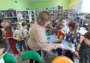 Pani Bibliotekarka rozdaje dzieciom książki