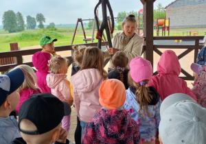 Dzieci stoją i przyglądają się pani prezentującej rzeźbę