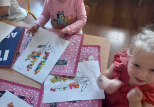 Dzieci wykonują pracę plastyczną przy stoliku