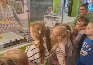 Dzieci słuchają pań, opowiadających o tajnikach produkcji lizaków