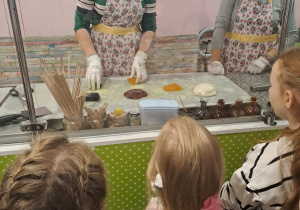 Panie prezentują dzieciom etapy produkcji lizaka
