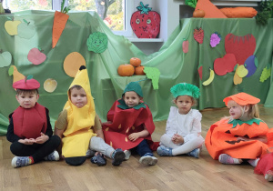 Dzieci przebrane za owoce pozują do zdjęcia na tle dekoracji