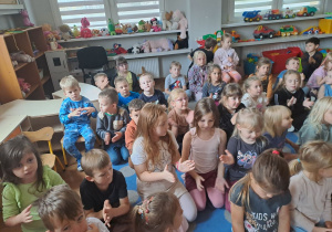 Dzieci siedzą na dywanie i klaszczą