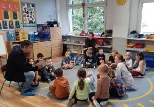 Dzieci siedzą na dywanie i słuchają bajki