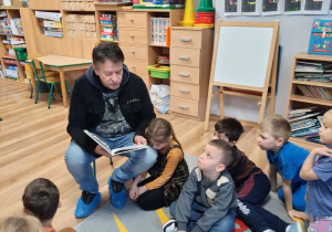 Dzieci siedzą na dywanie i słuchają bajki