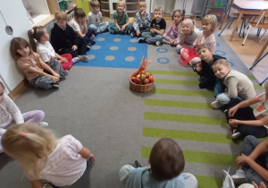 Dzieci siedzą w kole i rozmawiają na temat jabłek