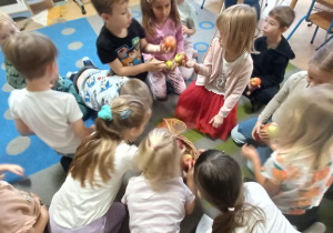 Dzieci trzymają jabłka w ręku i je porównują oraz opisują