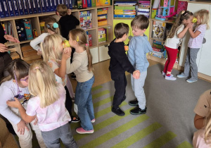 Dzieci w parach trzymają jabłka za pomocą czoła tak by nie spadło