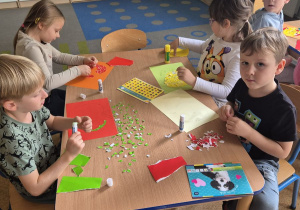 Dzieci wyklejają jabłka wydzieranką z kolorowego papieru