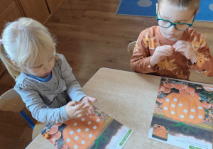 Dzieci wykonują prace plastyczną przy stolikach