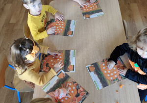 Dzieci wykonują prace plastyczną przy stolikach