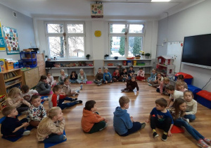 Dzieci siedzą na podłodze i słuchają opowieści pana z Felkowego Stryszka