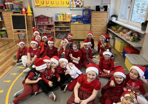 Figielki w mikołajkowych strojachsiedzą na dywanie