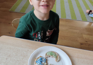 Wojtuś prezentuje udekorowane przez siebie pierniczki