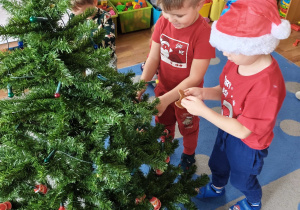 Dzieci wspólnie ubierają choinkę