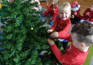 Dzieci wspólnie ubierają choinkę