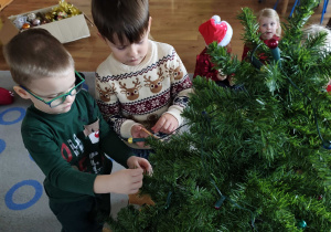 Dzieci wspólnie ubierają choinkę