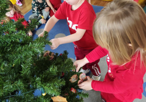 Dzieci wspólnie ubierają choinkę