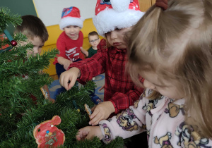 Dzieci wspólnie ubierają choinkę