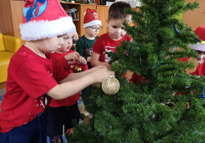 Dzieci wspólnie ubierają choinkę