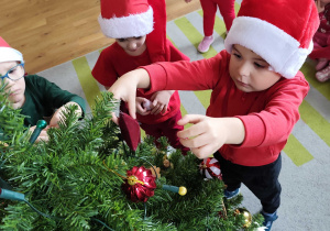 Dzieci wspólnie ubierają choinkę