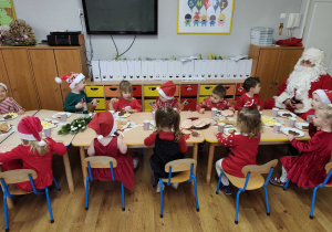 Dzieci siedzą przy stolikach podczas mikołajkowego poczęstunku