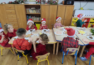 Dzieci siedzą przy stolikach podczas mikołajkowego poczęstunku