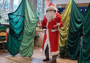 Mikołaj na tle dekoracji przedstawiającej drzewa