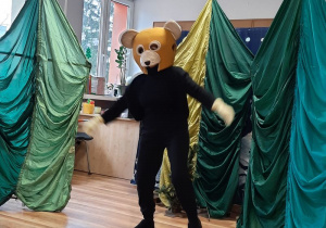 Taniec misia na tle dekoracji przedstawiającej drzewa