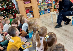 Dzieci siedzą na dywanie policjantka opowiada dzieciom